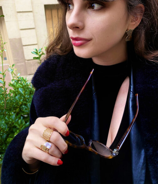 Bague avec un gros cristal portée par une femme avec des lunettes en bijou chic et tendance plaqué or joorn bijoux