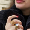 bague plaque en maille plaqué or portée par une femme brune au rouge à lèvre rouge