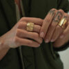 bague large avec des plis très moderne portée sur une main avec des tatouages