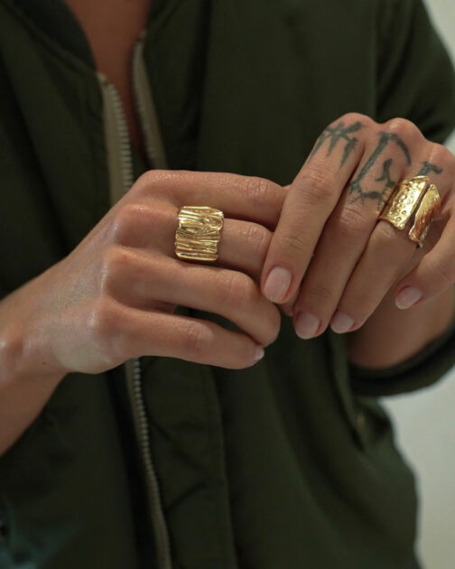 bague large avec des plis très moderne portée sur une main avec des tatouages