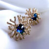 boucles d'oreilles en forme de fleur avec une pierre bleue au centre