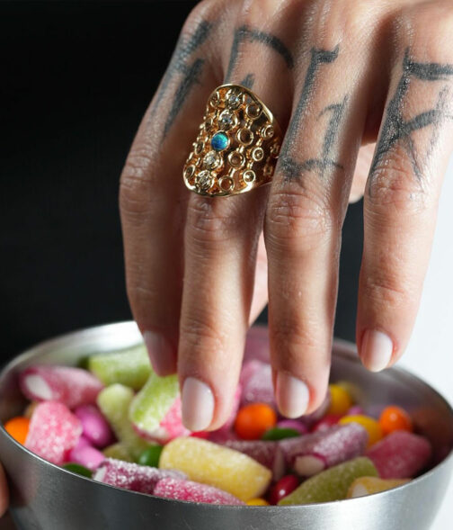 bague large pour femme sertie avec une opale bleu prenant des bonbons multicolores dans la main