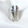 large bague argent pour femme posée sur un tissu blanc