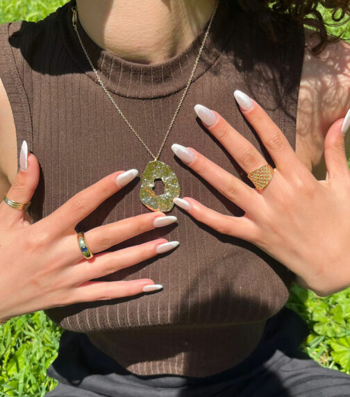 Collier femme martelé à la main pièce unique porté par une femme avec des bagues couleur or jaune